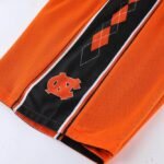 Orange reversible basketball shorts with black NC logo and argyle design detail