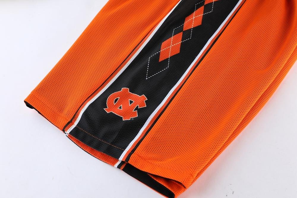 Orange reversible basketball shorts with black NC logo and argyle design detail