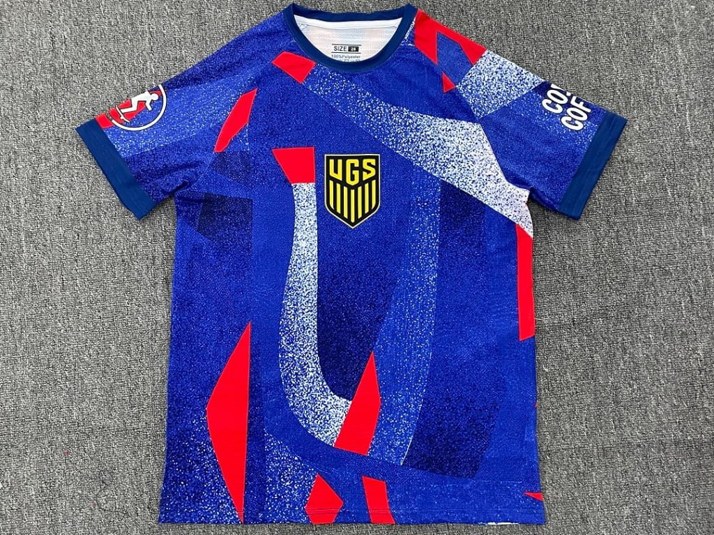 Blue full sublimation soccer jersey front view with UGS crest and abstract pattern