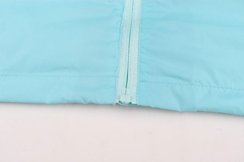 Close-up of light blue soccer windbreaker zipper and hem detail