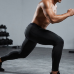 man performing dynamic lunge exercise while wearing black full-length compression leggings in gym
