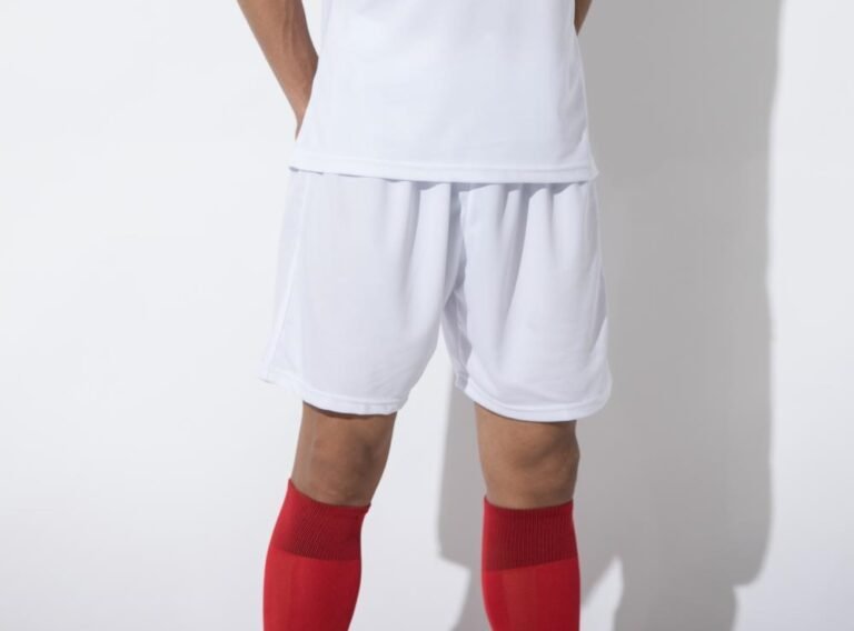 Man wearing white soccer shorts with red socks and white jersey