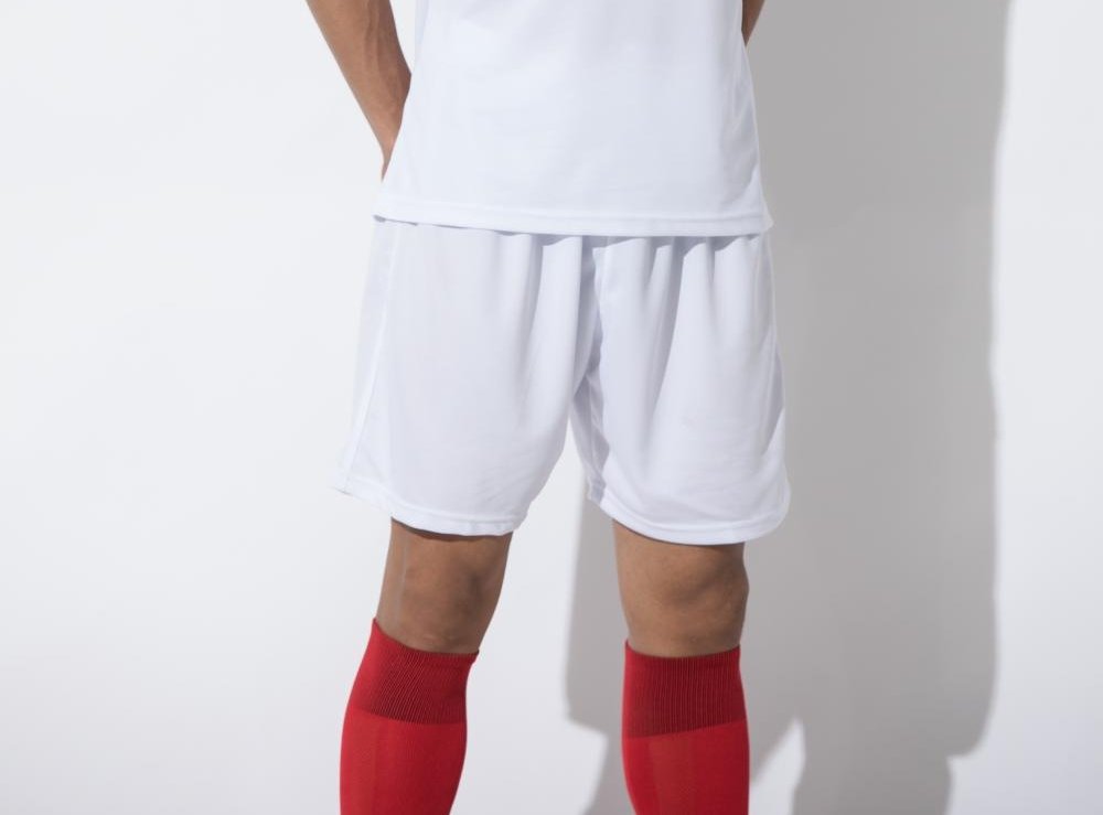 Man wearing white soccer shorts with red socks and white jersey