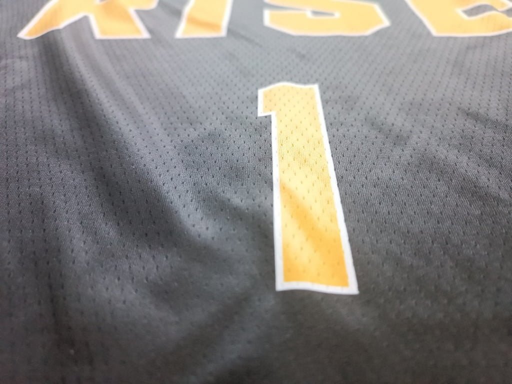 Close-up of yellow number print on black reversible basketball jersey fabric