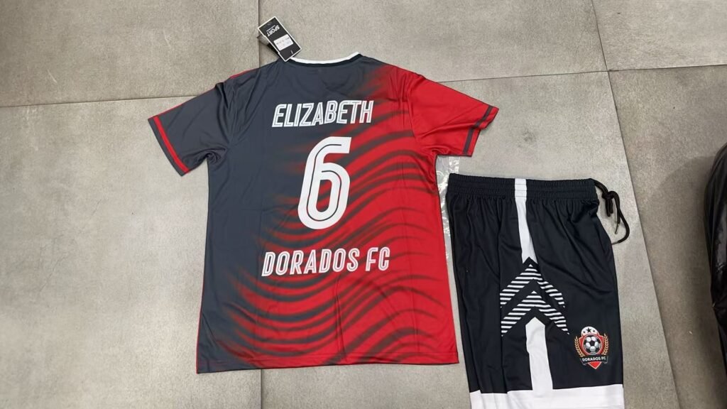 Custom black and red wave pattern sublimation soccer jersey back view with heat transfer name ELIZABETH and number 6, matching black shorts with white details.