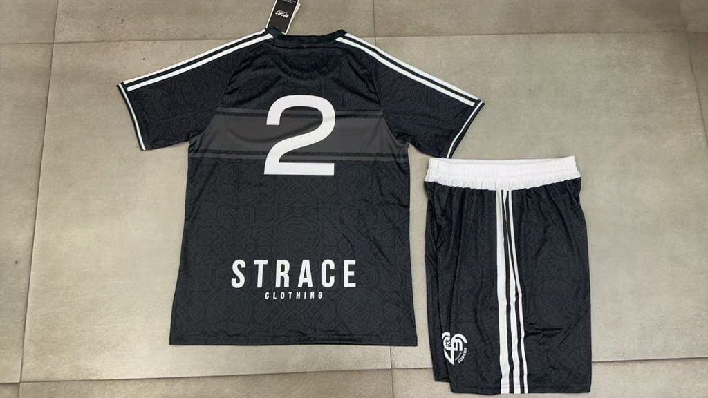 Custom black sublimation soccer kit back view with white shoulder stripes and side piping, featuring large heat transfer number 2 for small batch team customization.