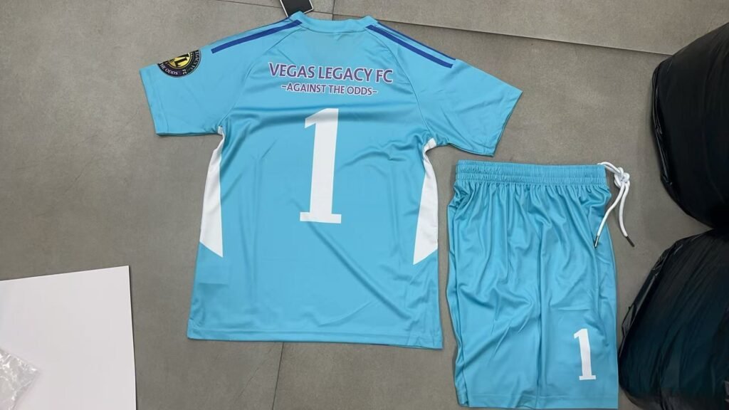 Custom light blue and white paneled soccer uniform back view, showing heat transfer team name VEGAS LEGACY FC and number 1 for wholesale customization.