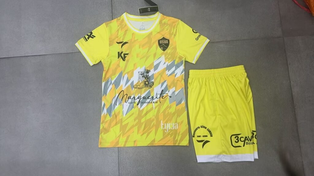 Custom yellow and orange geometric sublimation soccer jersey front view with heat transfer team name and complex abstract patterns, perfect for wholesale team apparel.