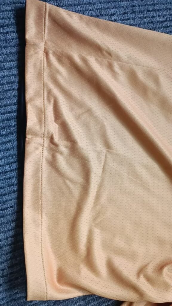Close-up of yellow reversible basketball shorts hem stitching and mesh fabric quality
