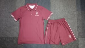 Flat lay shot of custom maroon 2-piece men's tennis apparel set featuring a polo shirt with white tipped collar and matching athletic shorts.