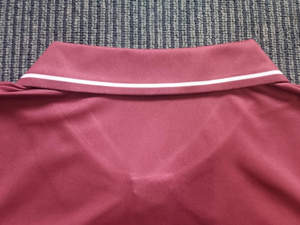 Back view of custom knitted ribbed polo collar with white contrast tipping on maroon athletic tennis jersey.