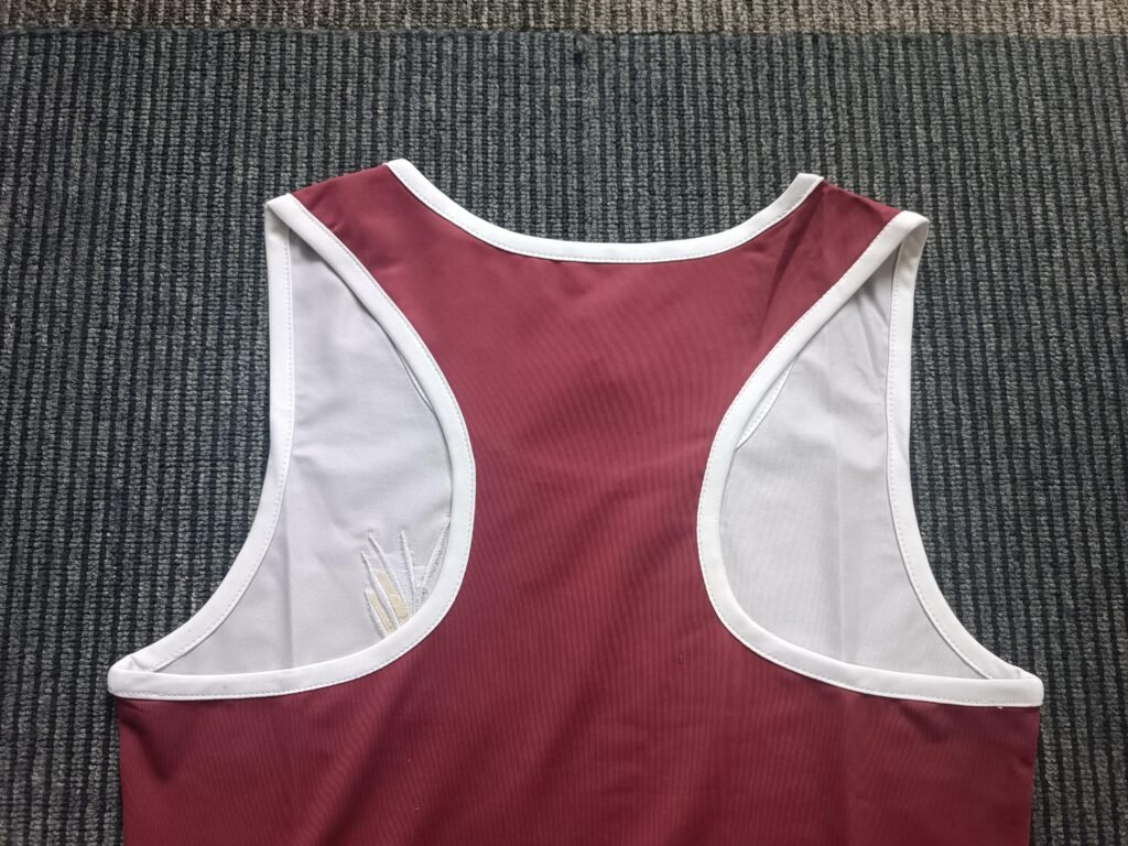 Detailed shot of white contrast trim on scoop neck and armholes of women's athletic tank top.