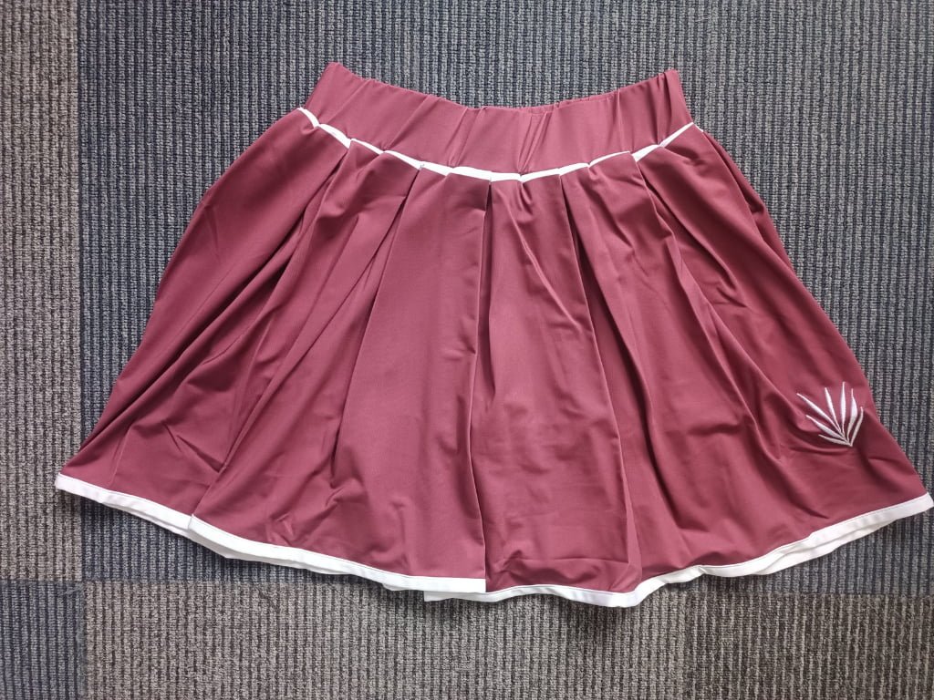 Flat lay shot of women's maroon pleated activewear skort featuring elastic waistband.